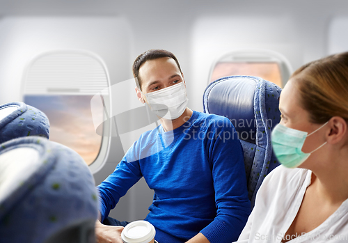 Image of couple of passengers in masks travelling by plane