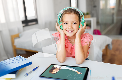 Image of girl in headphones with tablet computer at home