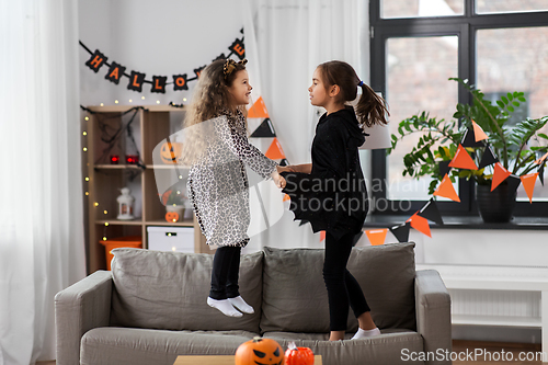 Image of girls in halloween costumes jumping on sofa