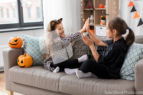 Image of girls in halloween costumes playing game at home