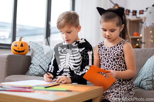 Image of kids in halloween costumes doing crafts at home