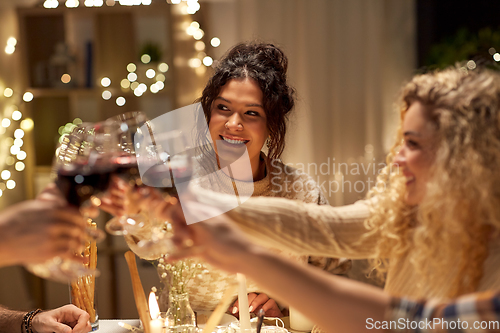 Image of happy friends drinking red wine at christmas party