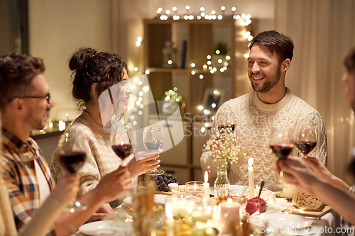 Image of happy friends drinking red wine at christmas party