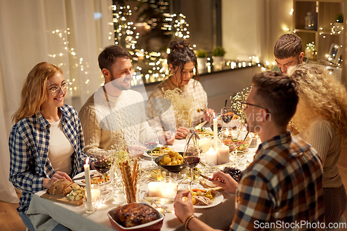 Image of happy friends having christmas dinner at home