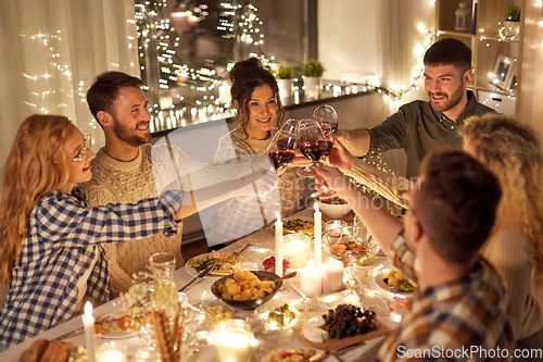 Image of happy friends drinking red wine at christmas party