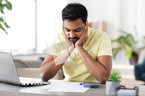 Image of man with calculator and papers working at home