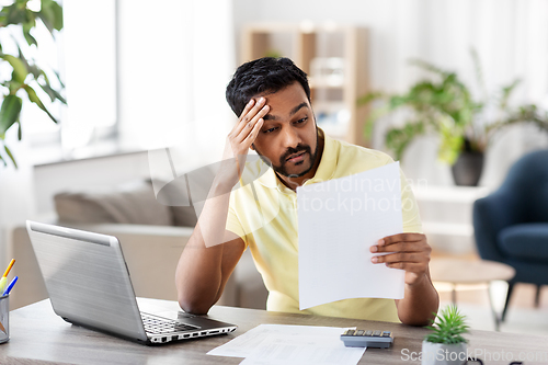 Image of man with calculator and papers working at home