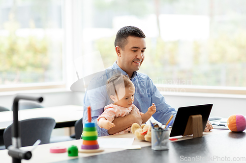 Image of father with baby working on tablet pc at home