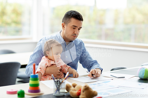 Image of father with baby working at home office