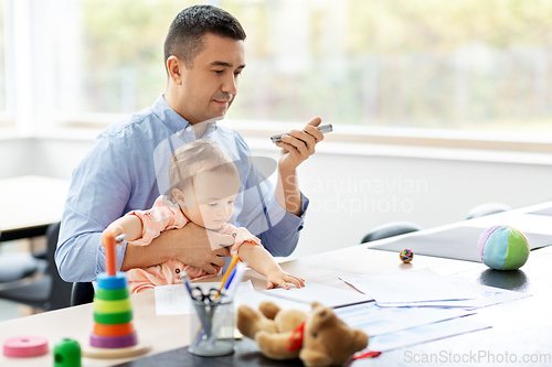 Image of father with baby and phone working at home office