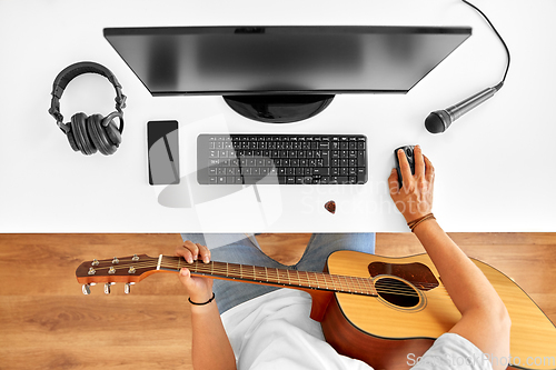 Image of young man with computer and guitar at table