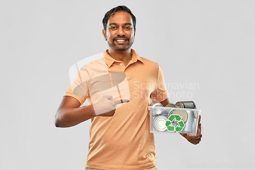 Image of smiling young indian man sorting metallic waste
