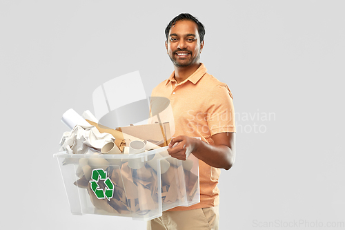 Image of smiling young indian man sorting paper waste