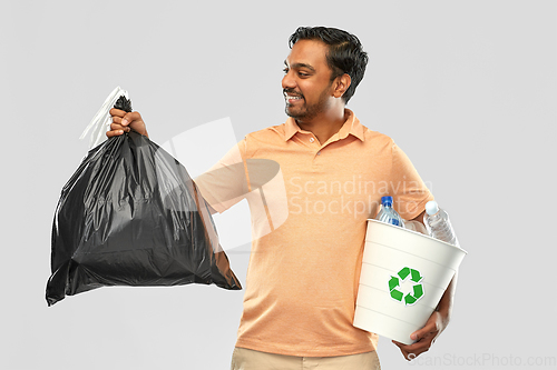 Image of smiling indian man sorting paper and plastic waste