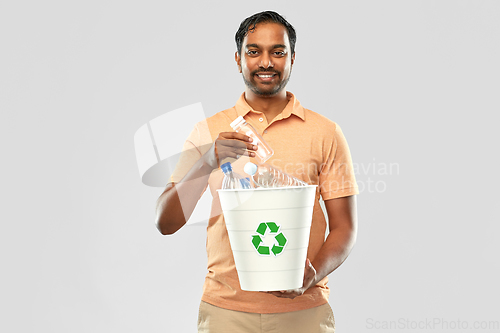 Image of smiling young indian man sorting plastic waste