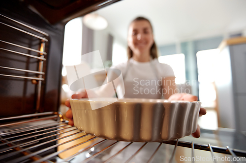 Image of woman cooking food in oven at home kitchen