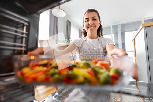 Image of woman cooking food in oven at home kitchen