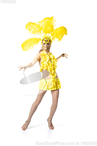 Image of Beautiful young woman in carnival, stylish masquerade costume with feathers dancing on white studio background.