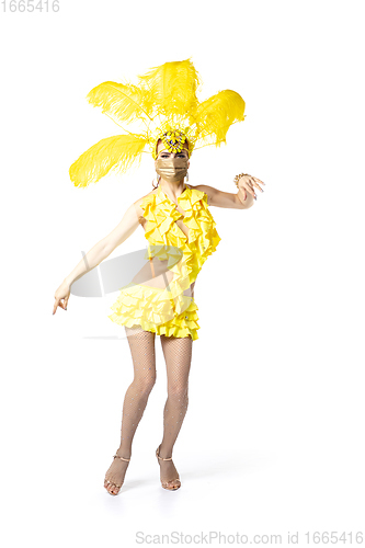 Image of Beautiful young woman in carnival, stylish masquerade costume with feathers dancing on white studio background.