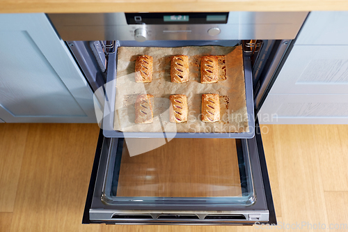 Image of baking tray with jam pies in oven at home kitchen