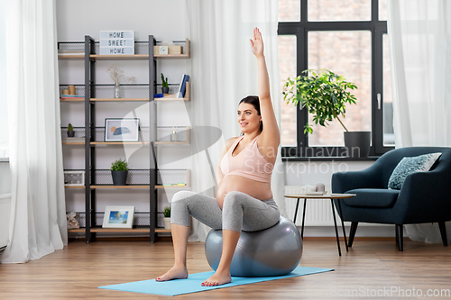 Image of pregnant woman exercising on fitness ball at home