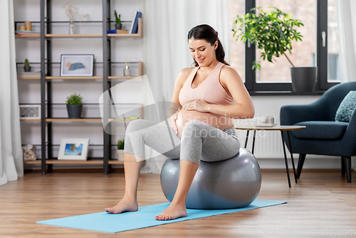 Image of pregnant woman exercising on fitness ball at home