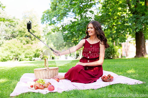 Image of happy woman with smartphone taking selfie at park