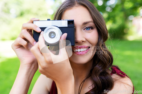 Image of happy woman with camera photographing at park