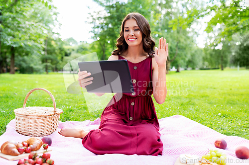 Image of woman with tablet pc having video call at picnic