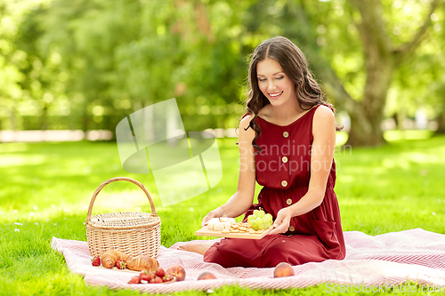 Image of happy woman with food and picnic basket at park