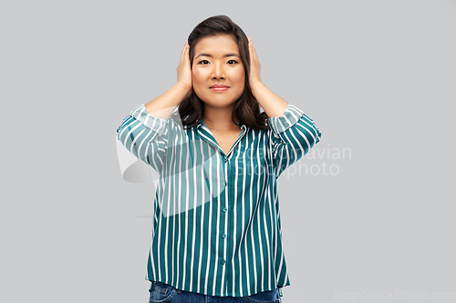 Image of asian woman closing ears by hands