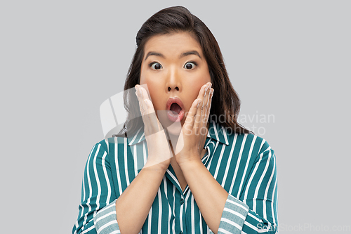 Image of shocked asian woman over grey background