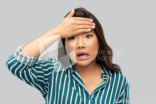 Image of stressed asian woman holding to her head