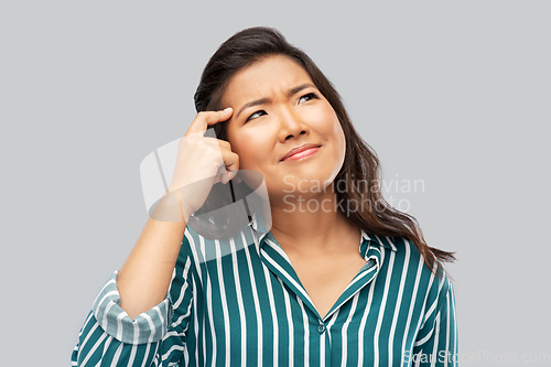 Image of thinking asian woman over grey background