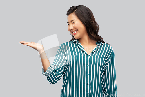 Image of happy asian woman holding something on hand