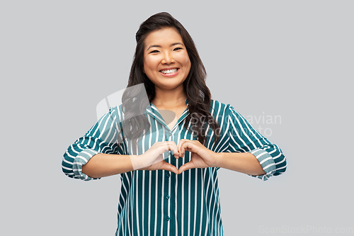 Image of happy asian woman showing hand heart gesture