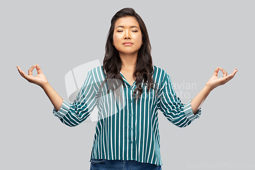 Image of happy asian woman meditating over grey background