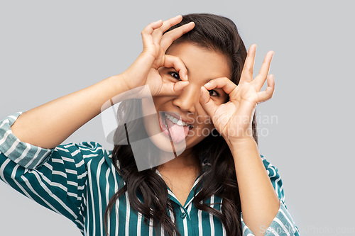 Image of smiling asian woman looking through finger glasses