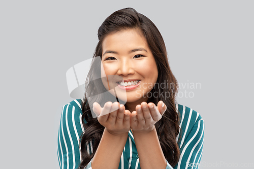 Image of happy asian woman holding something on hands