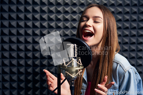 Image of Teen girl in recording studio with mic over acoustic absorber panel background