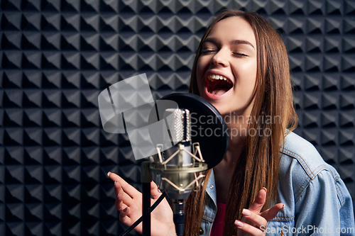 Image of Teen girl in recording studio with mic over acoustic absorber panel background