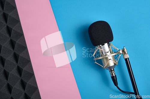 Image of Microphone and acoustic foam panel, ober pink and blue background