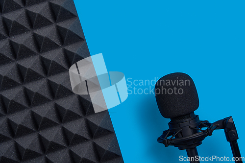 Image of Flat lay of microphone and acoustic foam panel, over blue background