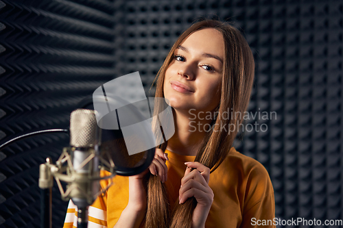 Image of Teen girl in recording studio with mic over acoustic panel background
