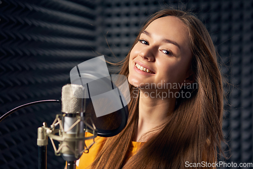 Image of Teen girl in recording studio with mic over acoustic panel background