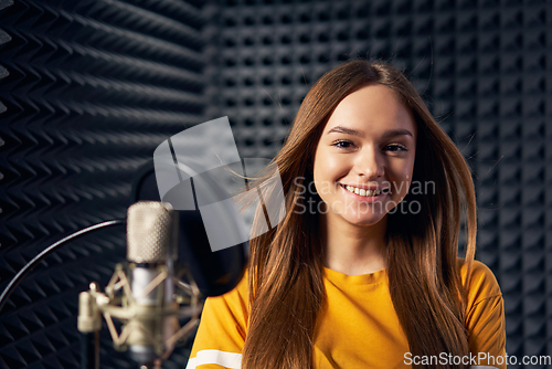 Image of Teen girl in recording studio with mic over acoustic panel background