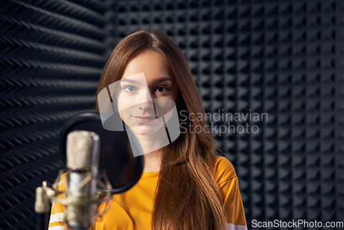 Image of Teen girl in recording studio with mic over acoustic panel background
