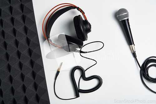 Image of Microphone, headphones and heart shaped cable on on white background with acoustic foam panel on side
