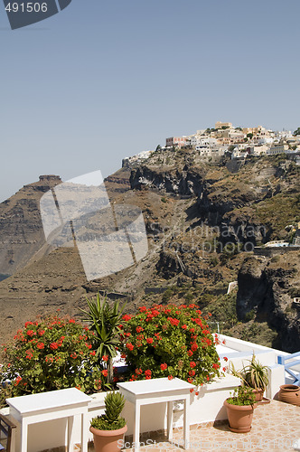 Image of tables with flowers and view of town on the caldera volcanic cli