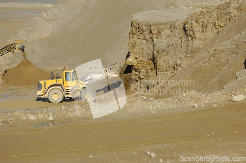 Image of A yellow wheel loader is working in gravel pit